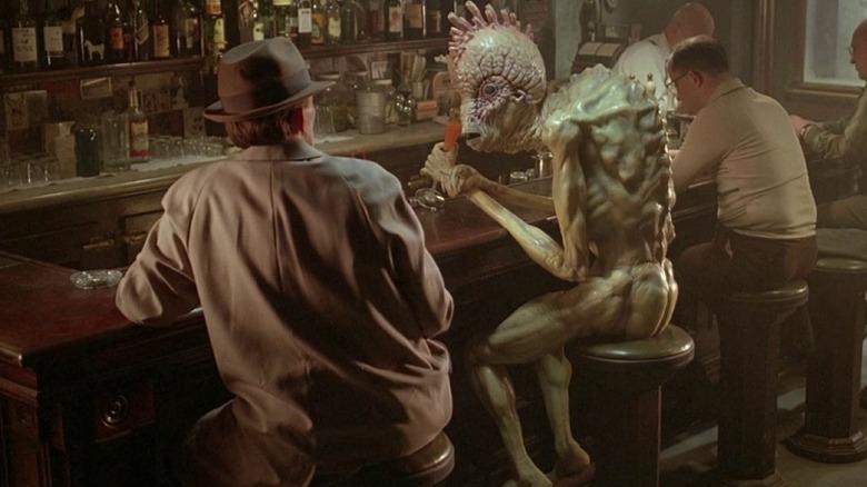 Peter Weller as Bill Lee sits at a bar with a mugwump in Naked Lunch