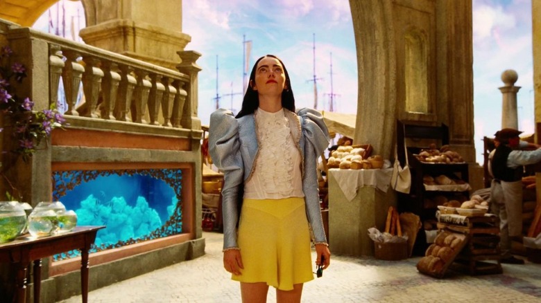 Emma Stone as Bella Baxter stands outside and looks up in Poor Things