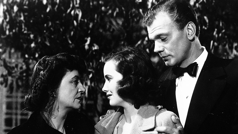 A tall man grasps a young woman's shoulders