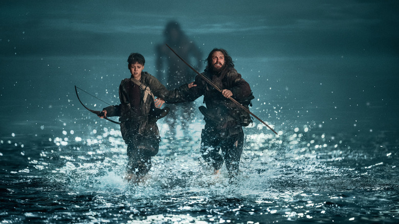 Aaron Taylor-Johnson as Jamie and Alfie Williams as Spike running through the water as an infected chases after them in 28 Years Later
