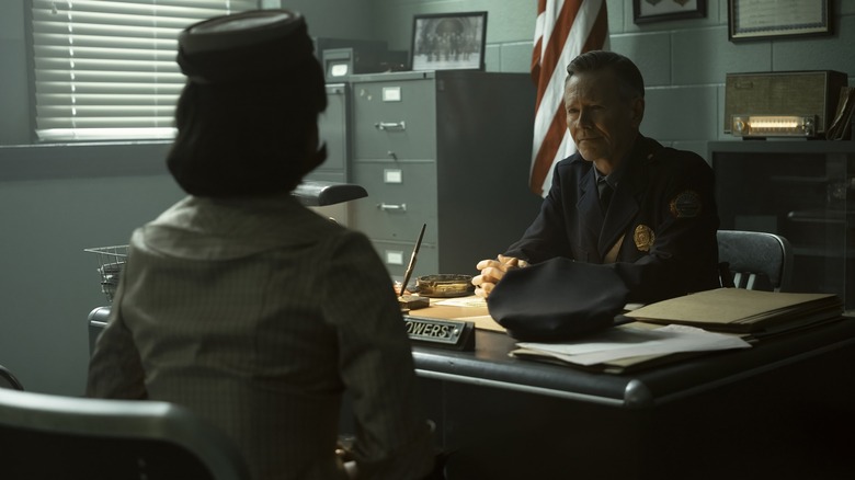 Taylour Paige as Charlotte Hanlon seated across Peter Outerbridge as Police Chief Clint Bowers in his office in It: Welcome to Derry