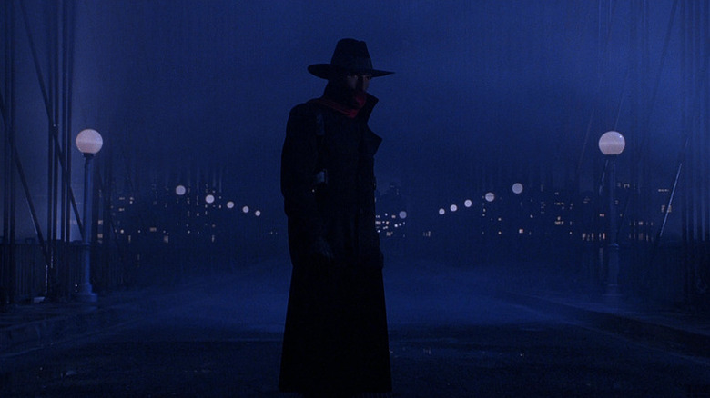 The Shadow (Alec Baldwin) standing on a dimly-lit street in "The Shadow."