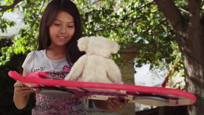 Diné girl holding hoverboard