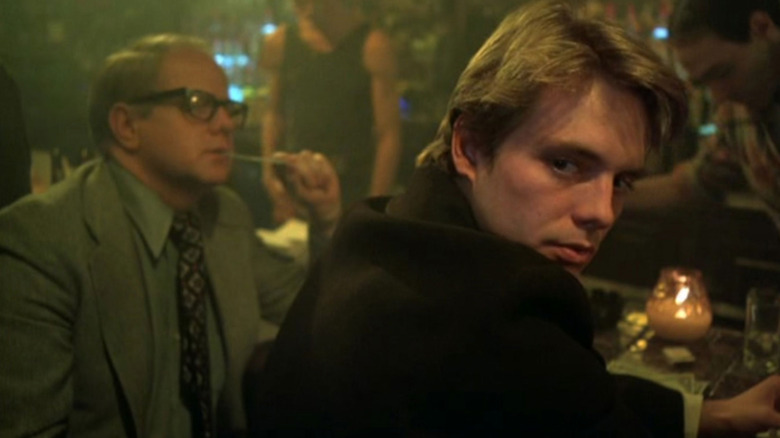 A man seated at a bar looks over his shoulder