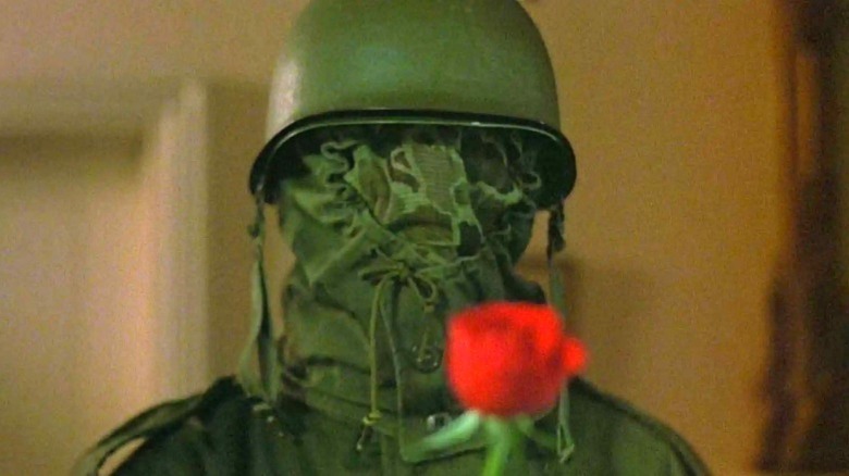 The killer holds up a rose