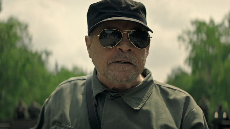 Mark Hamill as the Major wearing sunglasses and looking pleased in The Long Walk