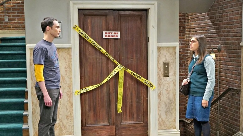 Sheldon and Amy talking in front of the broken elevator on The Big Bang Theory