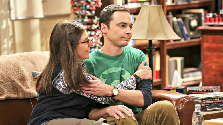 Amy Farrah Fowler, de Mayim Bialik, e Sheldon Cooper, de Jim Parsons, abraçando um sofá na teoria do Big Bang