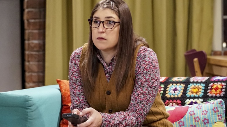 Amy holding a TV remote on The Big Bang Theory