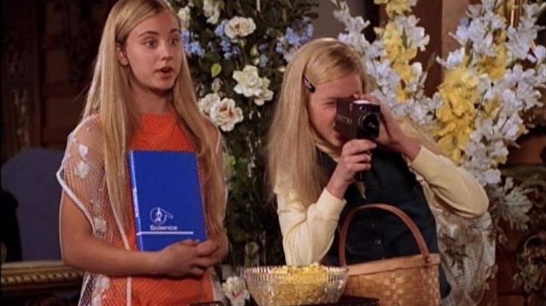 Kaley Cuoco as Maureen McCormick and Kaitlin Cullum asEve Plumb with a camera on the set of The Brady Bunch in Growing Up Brady