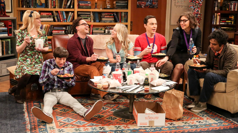 El elenco de Big Bang Theory se sienta en la sala de estar compartiendo una comida china para llevar.