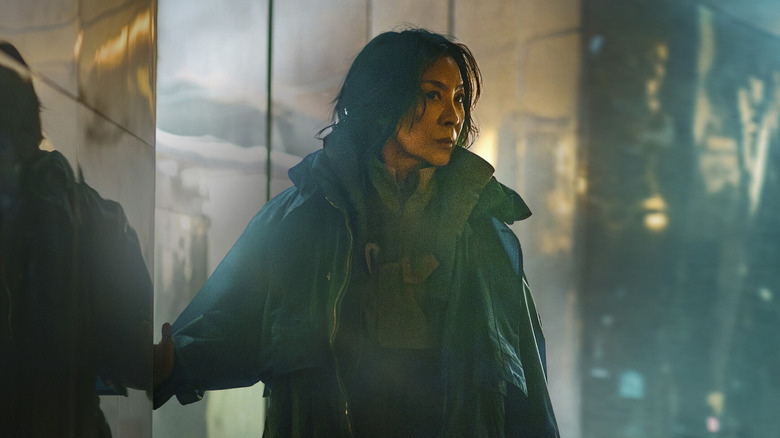 Michelle Yeoh as Olwen standing by panes of reflective glass in Blade Runner 2099