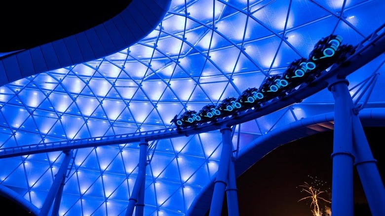 The TRON lightcycle ride at night, zooming along an elevated track