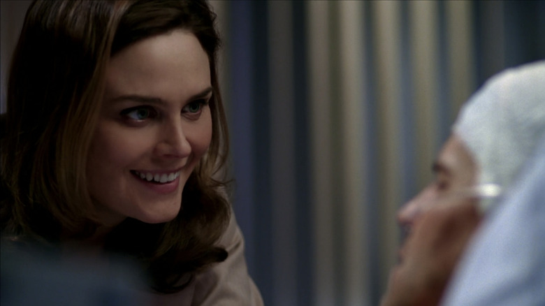 Emily Deschanel's Temperance Brennan leans in to talk to David Boreanaz's Seeley Booth who lays in a hospital bed in Bones