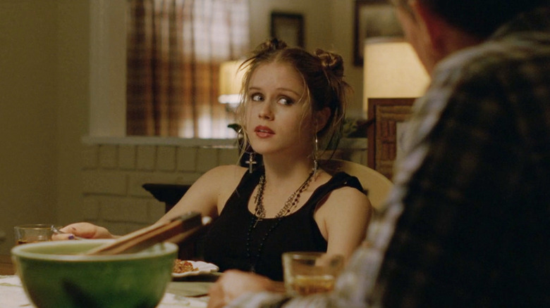 Erin Moriarty's Audrey Hart looks to her left as she sits at a dinner table in True Detective