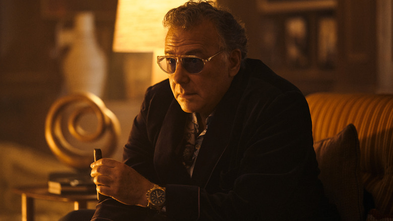 Paul Reiser as The Legend wearing sunglasses and an expensive watch in his living room in The Boys