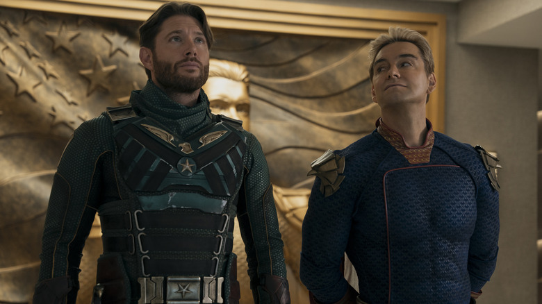 Antony Starr as Homelander standing next to Jensen Ackles as Soldier Boy in front of a gold engraving in The Boys