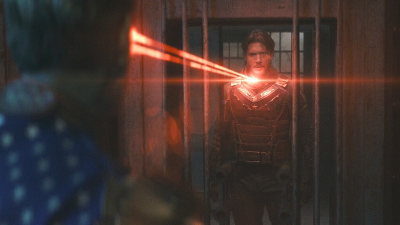 Antony Starr as Homelander directs an energy beam from his eyes from behind bars at Jensen Ackles as Soldier Boy in The Boys