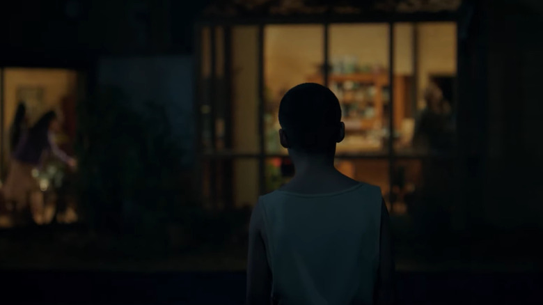 A young boy stands in front of a house to bring her back
