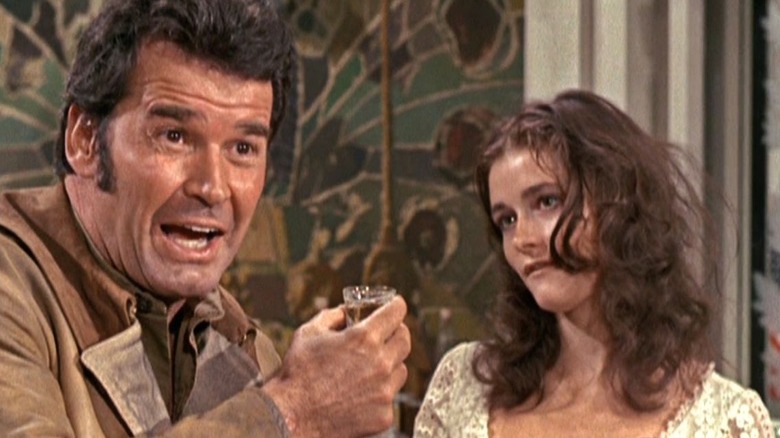 ஃபிராங்க் நிக்கோலஸாக ஜேம்ஸ் கார்னர் நிக்கோல்ஸில் உள்ள ஒரு பாரில் மார்கோட் கிடருக்கு அடுத்ததாக ரூத் ஆக நிற்கிறார்