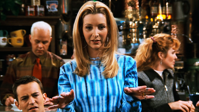 Lisa Kudrow's Phoebe Buffay holds her hands out as she stands in Central Perk in Friends
