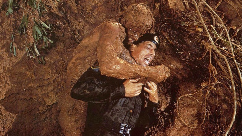 A mud-coated Sylvester Stallone attacks an enemy soldier as John Rambo in Rambo First Blood Part II