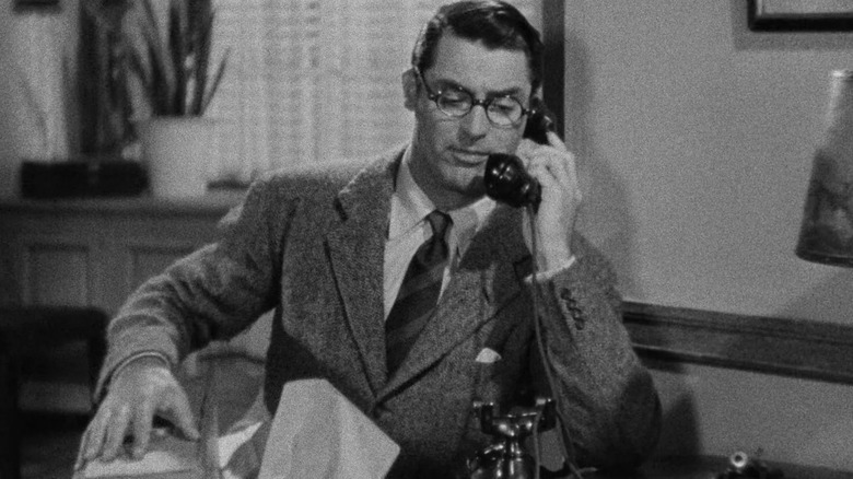 Dr. David Huxley van Cary Grant zit aan een bureau te telefoneren in Bringing Up Baby