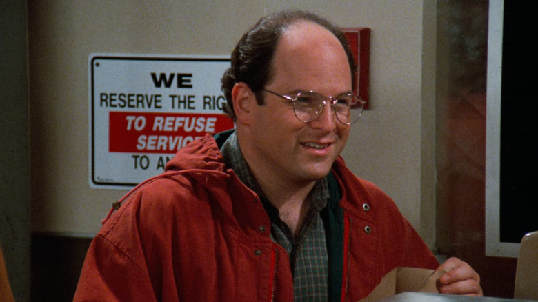 George Costanza (Jason Alexander) holding soup and smiling on Seinfeld
