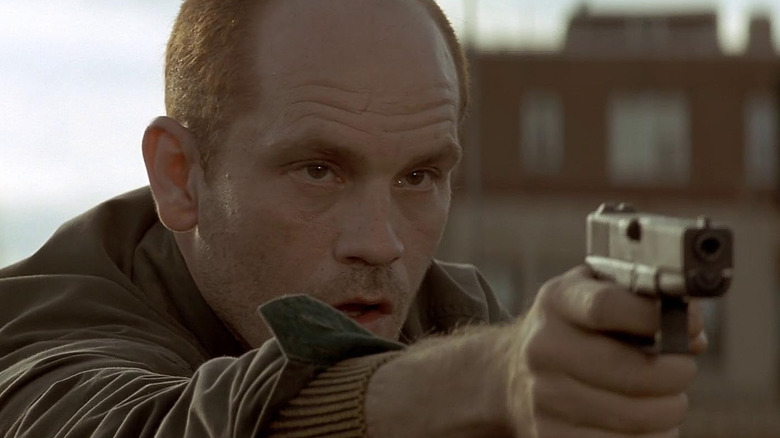 John Malkovich as assassin Mitch Leary pointing a gun in In the Line of Fire