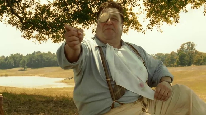 John Goodman as Big Dan Teague, the Cyclops, pointing at someone offscreen and smiling in O Brother, Where Art Thou?
