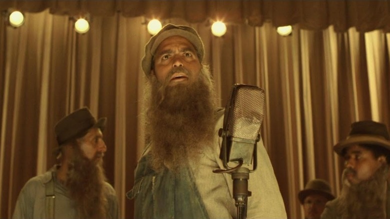 George Clooney as Ulysses in O Brother, Where Art Thou?, on stage in his Soggy Bottom Boys old man disguise