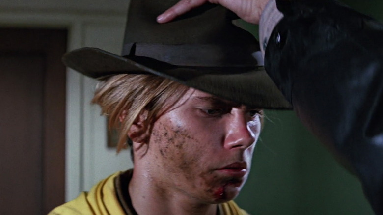 River Phoenix as Indiana Jones covered in dirt being given his fedora in The Last Crusade