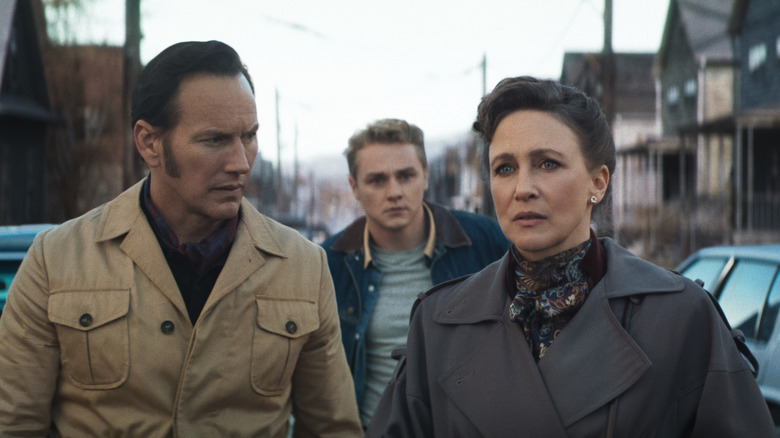Patrick Wilson as Ed Warren and Vera Farmiga as Lorraine Warren approaching a house with Ben Hardy as Tony following behind in The Conjuring: Last Rites