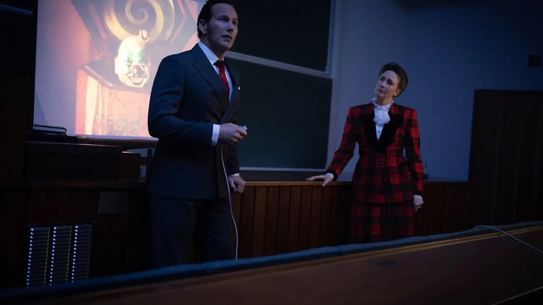 Ed and Lorraine Warren giving a lecture with evil clown pictures in The Conjuring: Last Rites