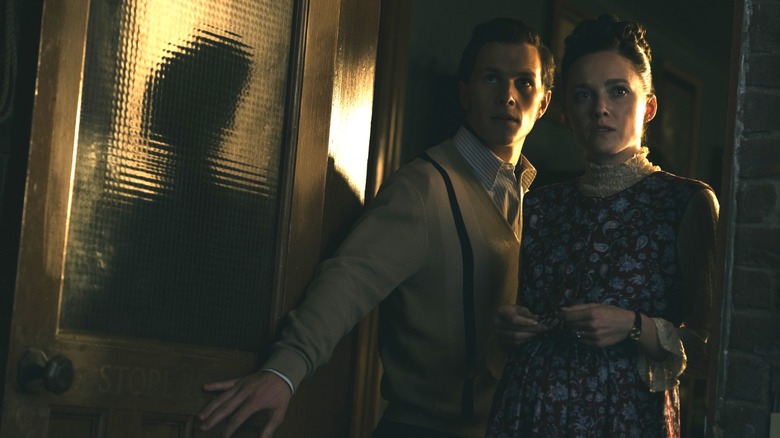 Orion Smith as young Ed Warren and Madison Lawlor as young Lorraine Warren standing by an open doorway in The Conjuring: Last Rites
