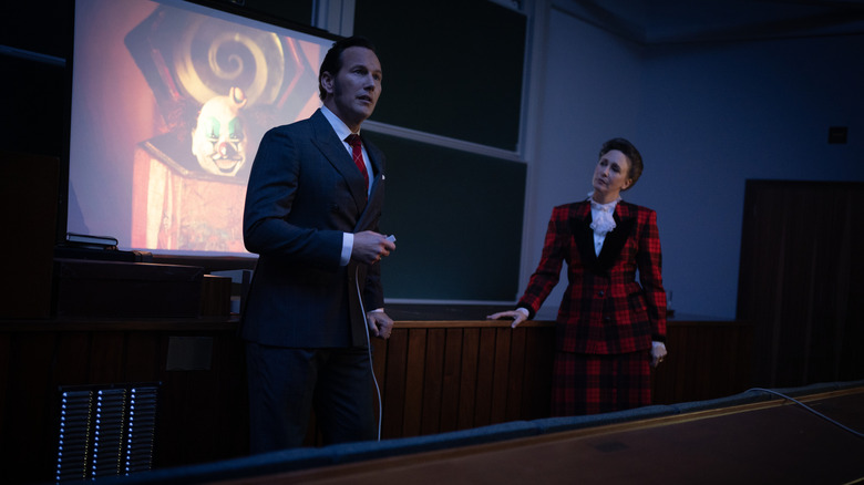 Patrick Wilson as Ed Warren and Vera Farmiga as Lorraine Warren give a presentation in a classroom setting in The Conjuring: Last Rites