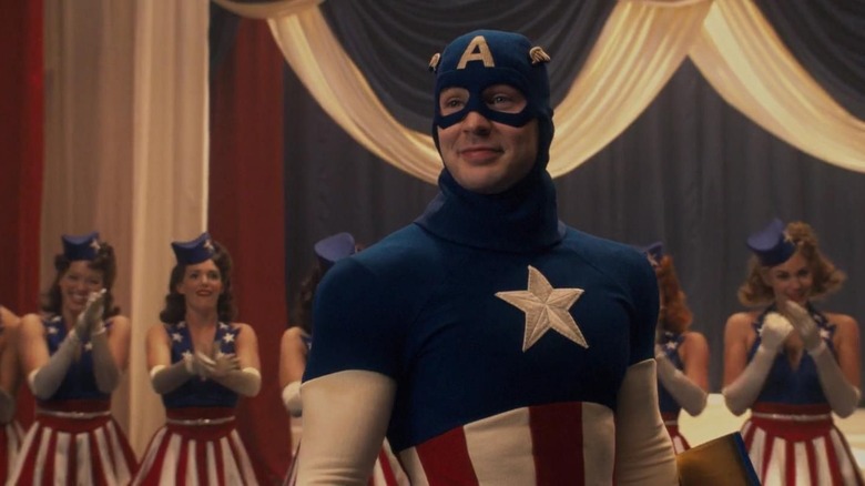 Captain America, in his stage costume, smiling with a bunch of women behind him in Captain America: The First Avenger