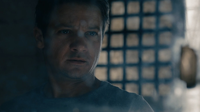 Jeremy Renner as Aaron Cross looks in a mirror in The Bourne Legacy