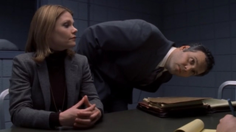 Detective Eames seated at a table while Detective Goren leans over to look at something. A scene from Law & Order: Criminal Intent