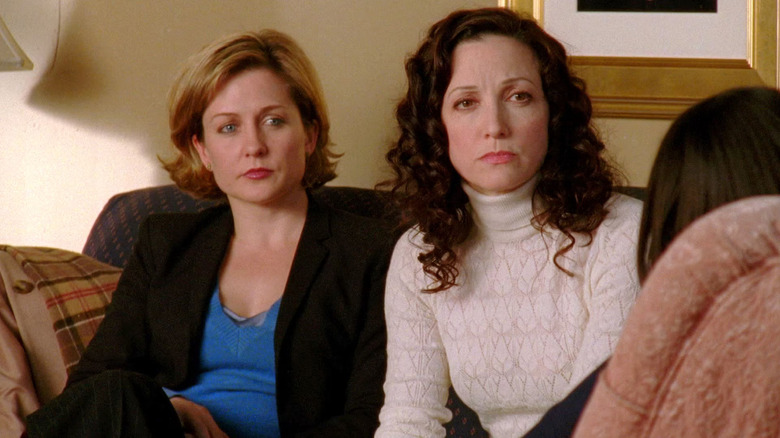 ADA Gaffney and DA Kibre, looking intensely at a young woman, seated on a couch. A scene from Law & Order: Trial By Jury.