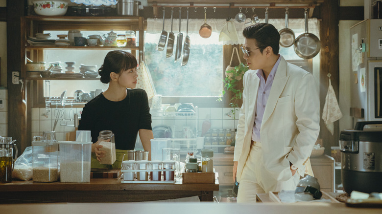 Han Beom-woo (Kang Ha-neul) approaches Mo Yeon-joo (Go Min-si) behind her kitchen counter in Tastefully Yours