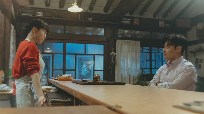 Moon-Joo (Go Min-Si) looks at Han Beom-Loo (Kang Ha-Neul) sitting in her kitchen in your taste