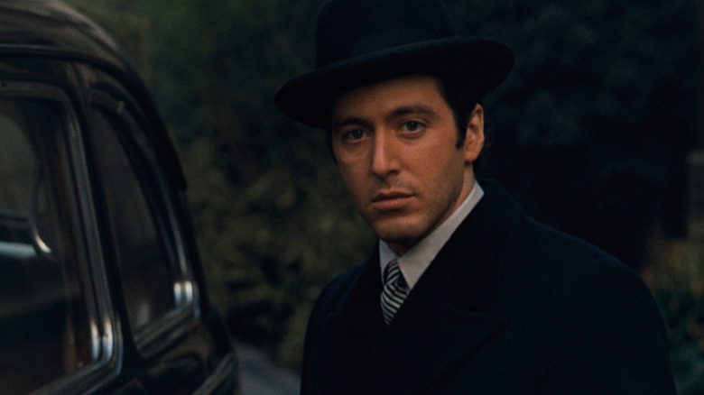 Michael Corleone standing next to a black car in The Godfather
