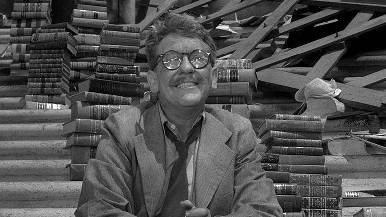 Man smiles surrounded by books