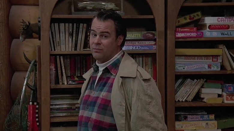 Dan Aykroyd's Roman Craig standing in front of a bookshelf of board games The Great Outdoors