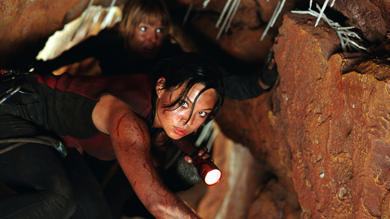 Juno creeping through a cave with a flashlight in The Descent