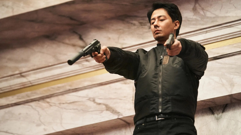 Kim Doo-sik (Zo In-sung) aims two pistols in Moving
