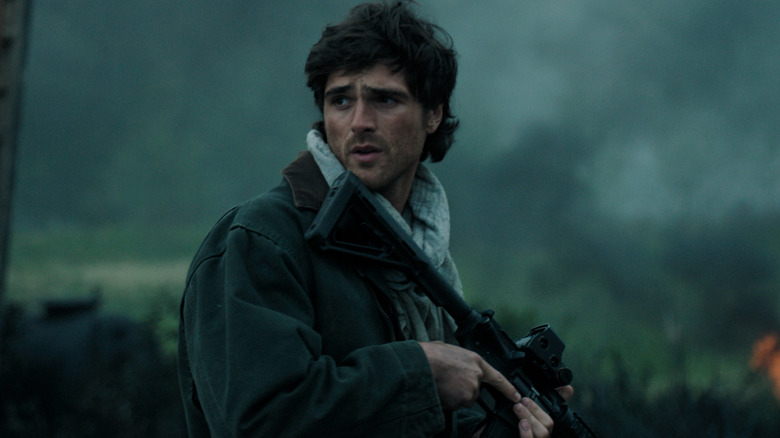 Hig has a gun and looks off to the side in The Dog Stars