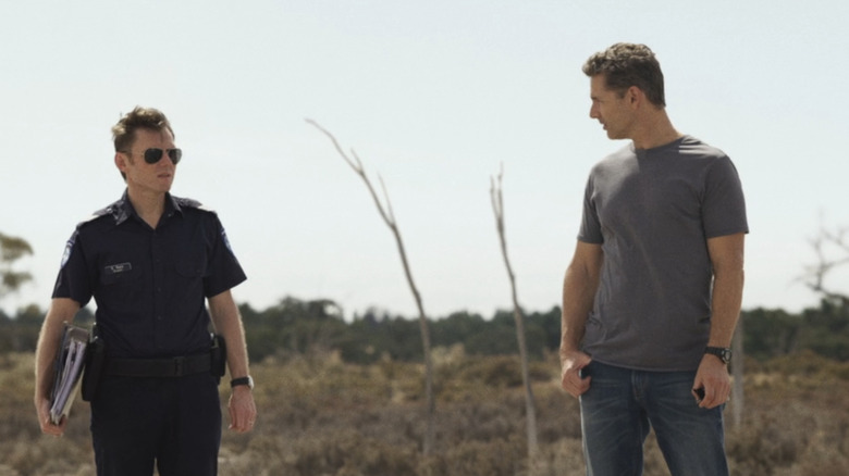 Keir O'Donnell's Greg Raco stands next to Eric Bana's Aaron Falk in a field in The Dry