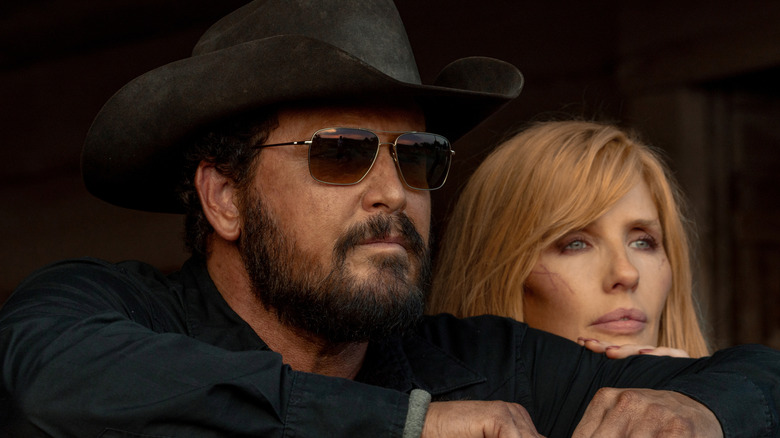 Cole Hauser's Rip Wheeler looks off into the distance wearing shades next to Kelly Reilly's Beth Dutton in Dutton Ranch